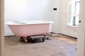 Pink bathtub placed on dolly in bare room.